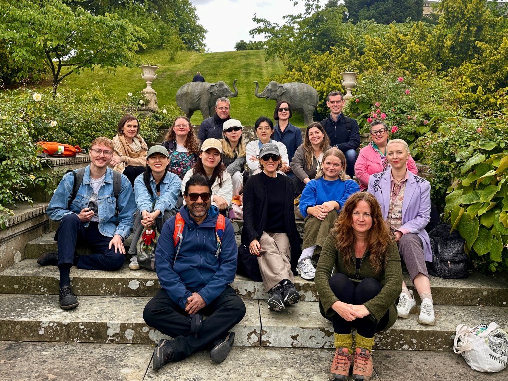 A group of academics from mixed ethnic backgrounds sit on stairs in a british garden