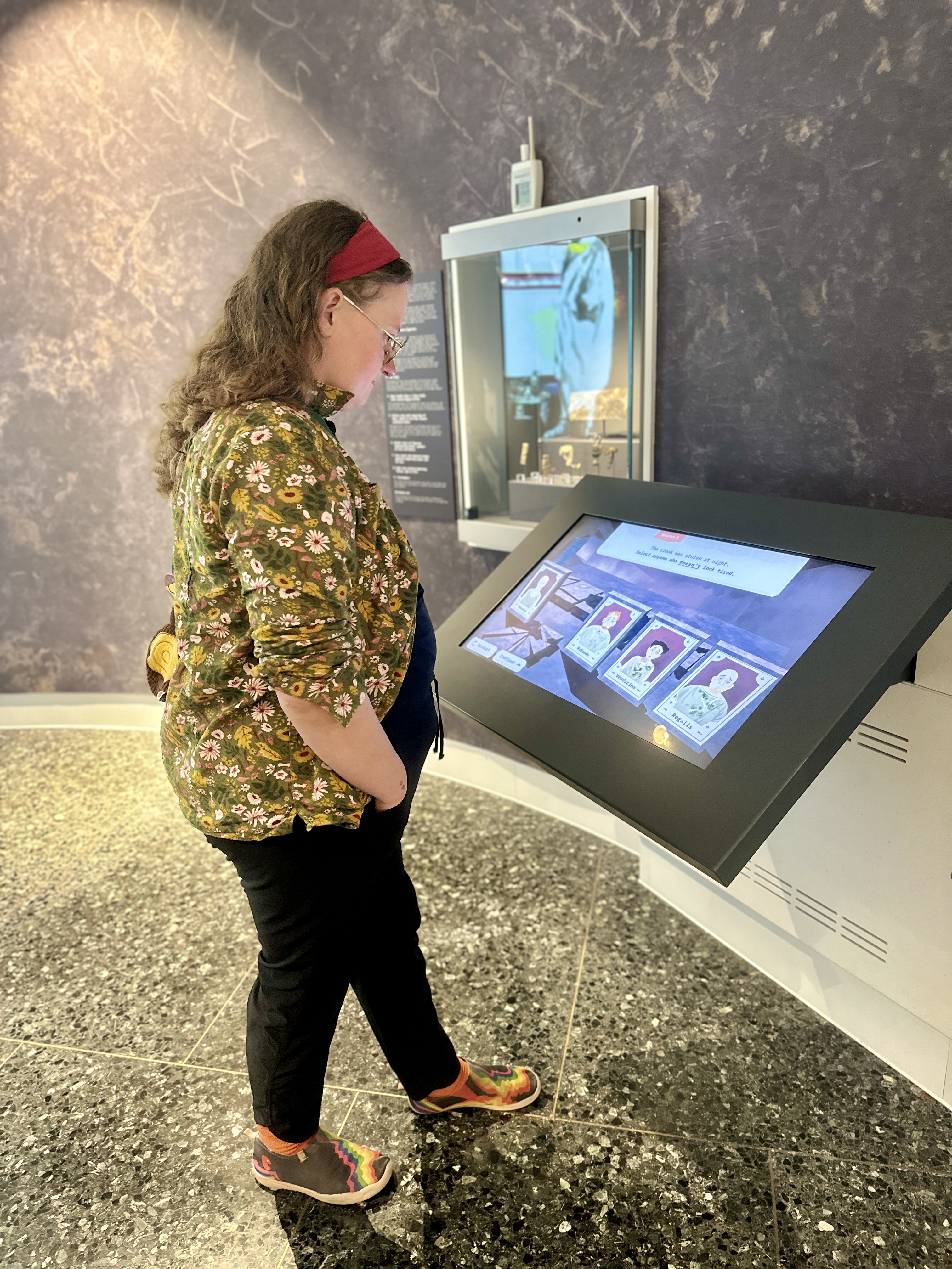 A person stands in front of an interactive display in a museum gallery